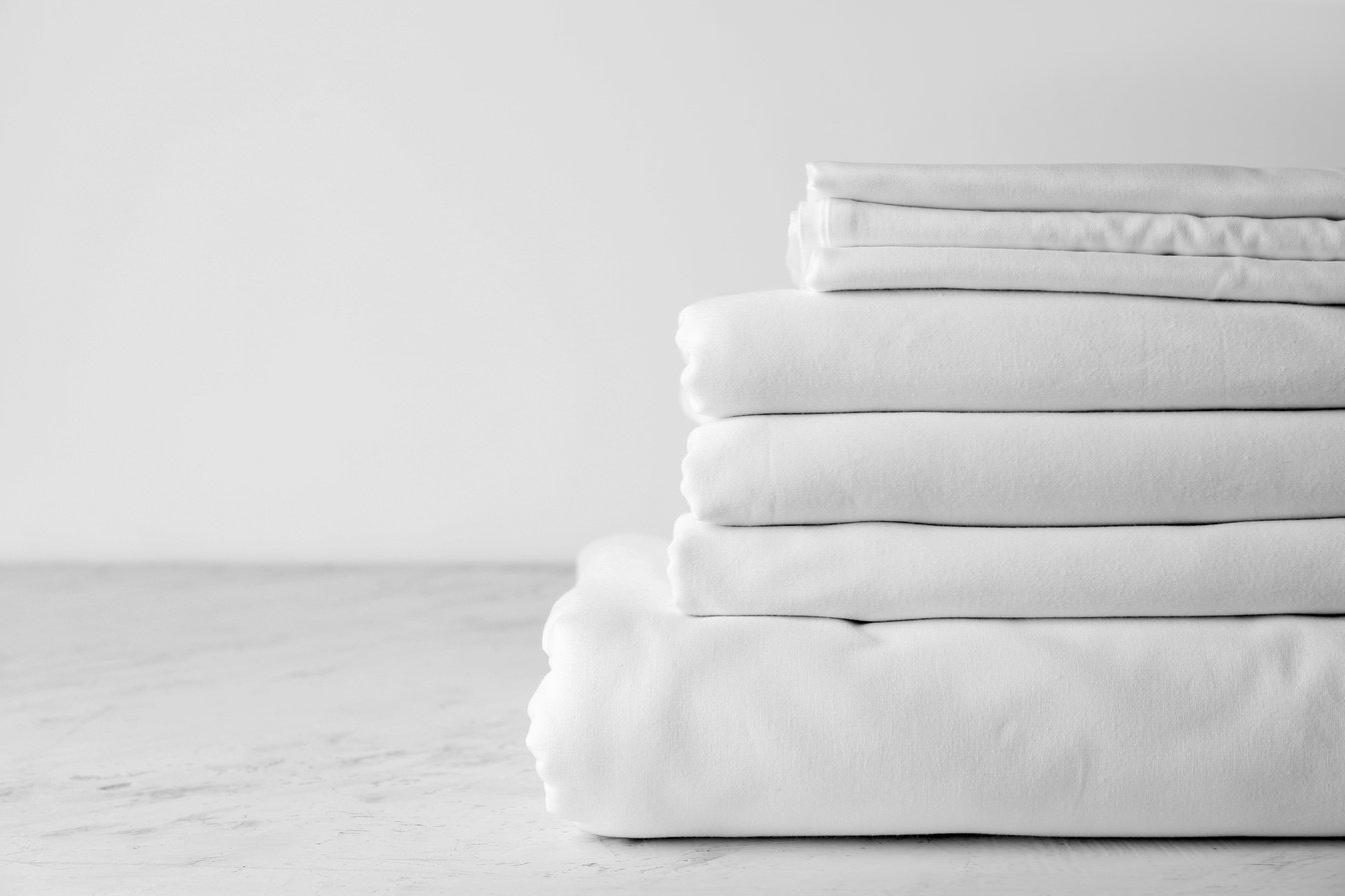 Stack of Clean Bed Sheets on Table